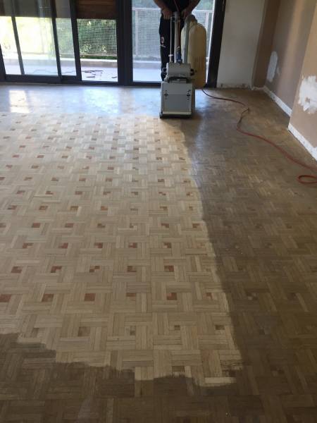 Remise en état par ponçage d'un parquet chêne avec des incrustations de cabochons rouges à Marseille